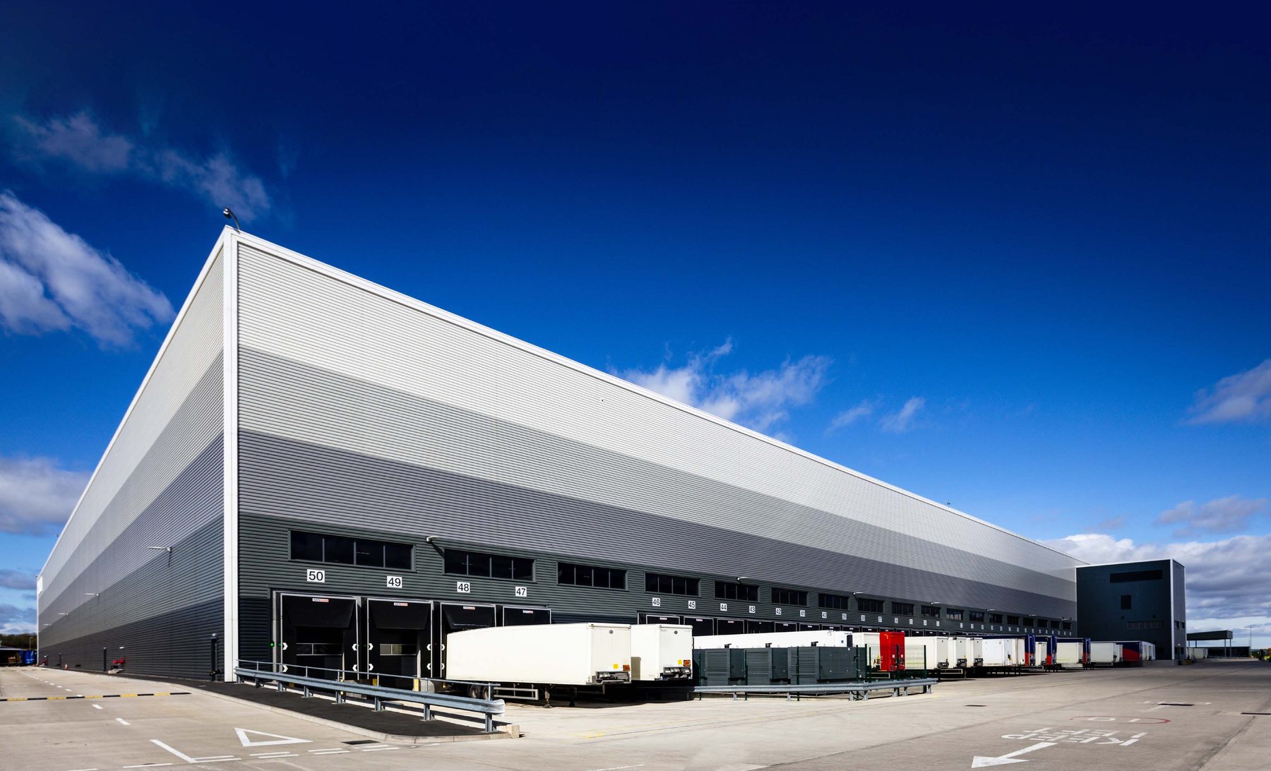 Skygate distribution centre at East Midlands Gateway under a clear blue sky, with loading docks along its length